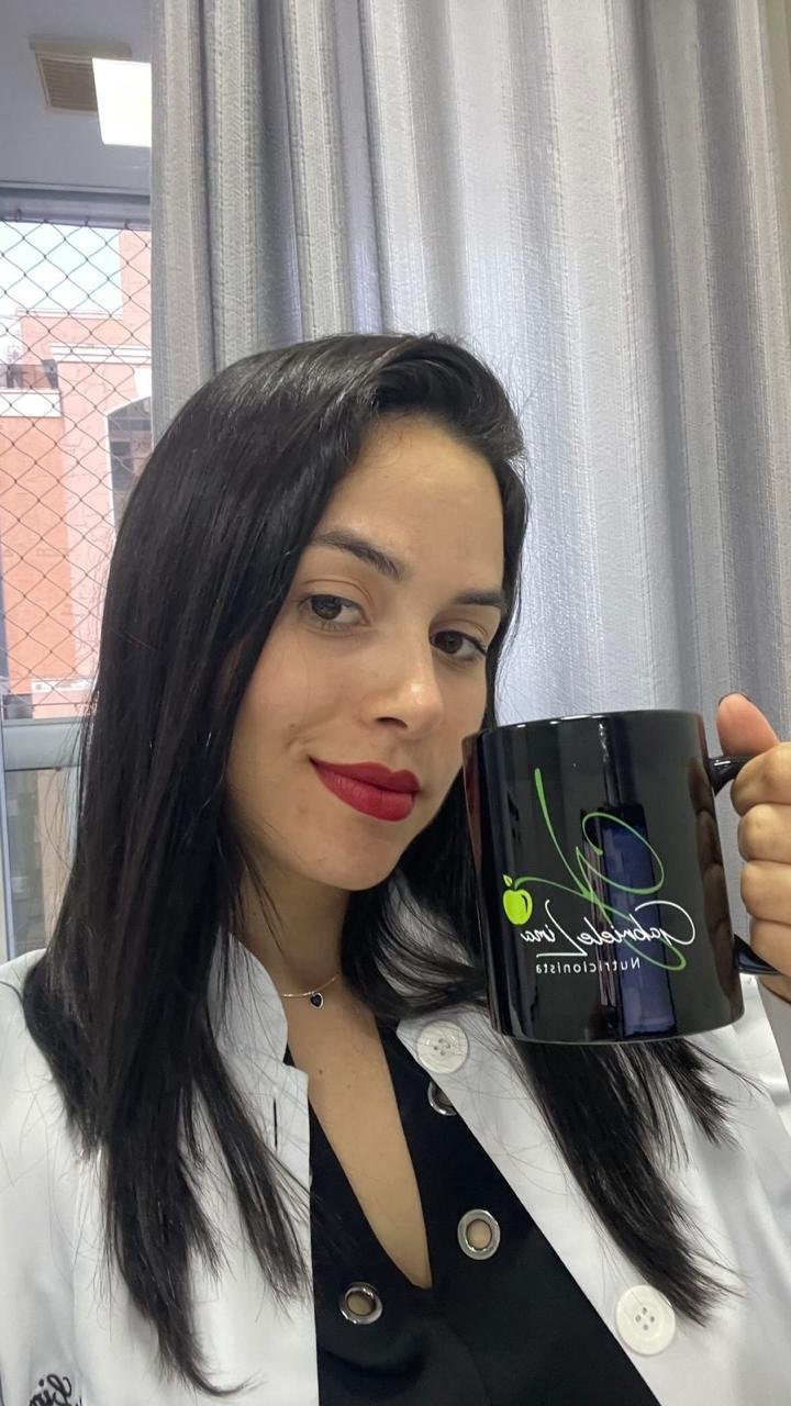 Gabriele Lima de jaleco, segurando uma caneca com a sua marca.