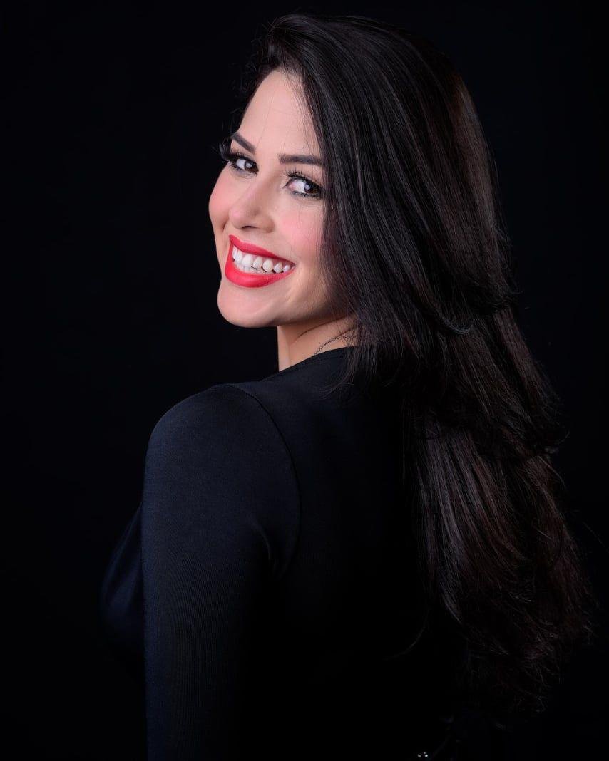 Gabriele Lima em retrato profissional de perfil, sorrindo, com fundo escuro.